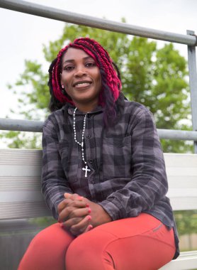 Mutlu Afrikalı kadın güzel park ortamında huzur içinde dinleniyor. Otantik yaşam tarzı portresi sağlıklı ve doğal dış mekan sükunetini gösteriyor..