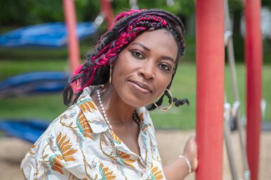 Renkli çocuk parkında çalışan Afro-Amerikan kadın eğitimci. Açık havada çocuk bakımı erken eğitim ve öğretim için ideal öğrenim ortamında çocuk bakımı öğretmeni portresi