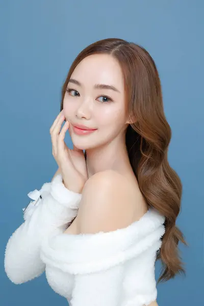 年轻的亚洲美女卷曲长发 脸上有韩国式的妆容 背景是孤立的蓝色 皮肤洁白完美 面部治疗 整形外科 — 图库照片