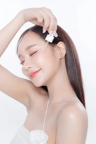 きれいな新鮮な肌の韓国の構造を持つ若いアジアの女性の長い髪は 白い背景に血清を適用します 女性モデルフェイスケア フェイシャルトリートメント 化粧品 美容とスパ アジアの女性の肖像画 — ストック写真