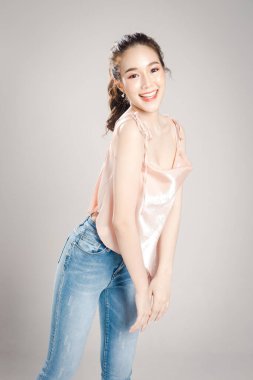 Güzel genç Asyalı kadın, gri afişte izole edilmiş kameraya poz vermekten mutlu.. 