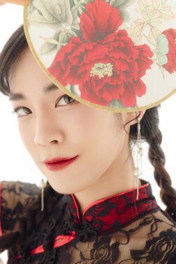 Yeni Çin yılın kutlu olsun. Modern Cheongsam Qipao elbisesi giyen Asyalı kadının beyaz arka planda bir yelpaze tutarken yakın plan fotoğrafı. Şirin bir kadın model..