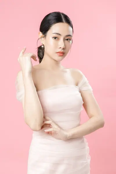 亚洲女人 有着美丽的脸蛋和完美洁净的肌肤 迷人的女性模特儿 有着自然的妆容和闪亮的眼睛 有着粉红色的孤立的背景 面部治疗 美感概念 — 图库照片