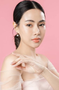Güzel yüzlü ve mükemmel temiz tenli Asyalı bir kadın. Doğal makyajı ve pembe izole edilmiş arka planda ışıl ışıl gözleri olan sevimli bir kadın modeli. Yüz bakımı, kozmetoloji, güzellik konsepti..