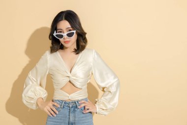 Güzel yüzlü ve mükemmel temiz tenli Asyalı bir kadın. Bej izole arka planda, seksi elbiseli, lüks modaya uygun bir kadın model. Kozmetoloji, E-ticaret, Çevrimiçi alışveriş kavramı.