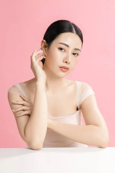 美しい顔と完璧なきれいな新鮮な肌を持つアジアの女性 自然なメイクとピンクの隔離された背景に輝く目を備えたかわいい女性モデル フェイシャルトリートメント 化粧品 美容コンセプト — ストック写真
