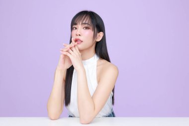 Güzel, genç, Asyalı bir kadın, uzun saçlı, doğal makyajlı, temiz tenli, izole bir menekşe. Tatlı kız portresi, yüz bakımı, vücut bakımı, güzellik ve güzellik merkezi..