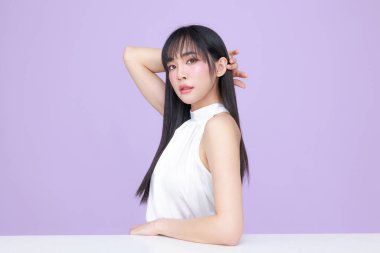 Güzel, genç, Asyalı bir kadın, uzun saçlı, doğal makyajlı, temiz tenli, izole bir menekşe. Tatlı kız portresi, yüz bakımı, vücut bakımı, güzellik ve güzellik merkezi..