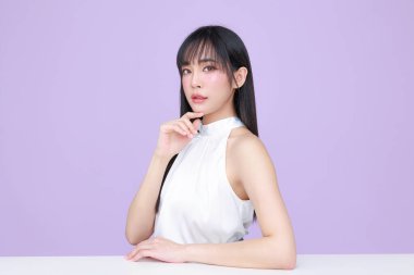 Güzel, genç, Asyalı bir kadın, uzun saçlı, doğal makyajlı, temiz tenli, izole bir menekşe. Tatlı kız portresi, yüz bakımı, vücut bakımı, güzellik ve güzellik merkezi..