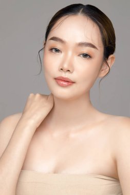 Gri arka planda mükemmel temiz cilde sahip güzel bir Asyalı kadın modeli. Yüz bakımı, yüz bakımı, kozmetik, estetik cerrahi stüdyoda güzel bir kız portresi..