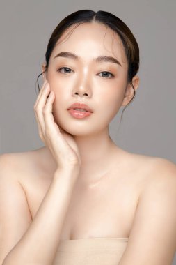 Gri arka planda mükemmel temiz cilde sahip güzel bir Asyalı kadın modeli. Yüz bakımı, yüz bakımı, kozmetik, estetik cerrahi stüdyoda güzel bir kız portresi..