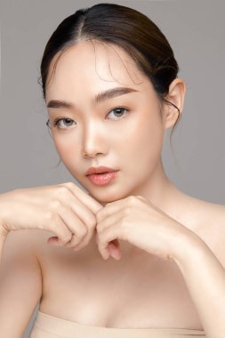 Gri arka planda mükemmel temiz cilde sahip güzel bir Asyalı kadın modeli. Yüz bakımı, yüz bakımı, kozmetik, estetik cerrahi stüdyoda güzel bir kız portresi..