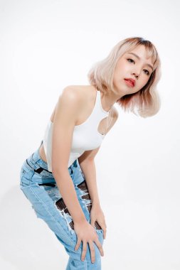 Modaya uygun Asyalı kadın, kısa saçlı, mükemmel vücutlu. Doğal makyajlı, beyaz tenha arka planda ışıl ışıl gözleri olan sevimli bir kadın modeli. Yüz bakımı, kozmetoloji, güzellik konsepti..