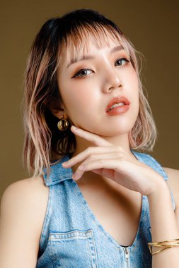 Kendine güvenen Asyalı kısa saçlı, mükemmel vücutlu bir kadın. Bej izole edilmiş arka planda seksi ve ışıl ışıl gözleri olan sevimli bir kadın modeli. Yüz bakımı, kozmetoloji, güzellik konsepti..