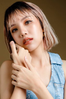 Kendine güvenen Asyalı kısa saçlı, mükemmel vücutlu bir kadın. Bej izole edilmiş arka planda seksi ve ışıl ışıl gözleri olan sevimli bir kadın modeli. Yüz bakımı, kozmetoloji, güzellik konsepti..