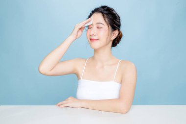 Mükemmel ciltli güzel bir Asyalı kadın. İzole edilmiş mavi arka planda taze hidratlı ve doğal makyajlı mutlu kız modeli. Kozmetik, güzellik ve güzellik, sağlık, estetik cerrahi.