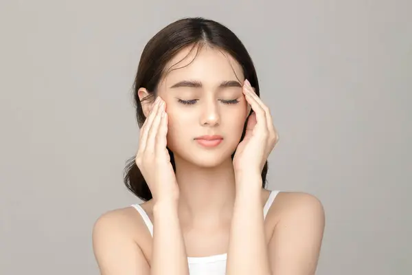 美しい若いアジアの女性モデルは 灰色の背景に完璧なきれいな新鮮な肌で彼女の顔に触れます フェイスケア フェイシャルトリートメント 化粧品 プラスチック手術 スタジオで素敵な少女の肖像画 — ストック写真