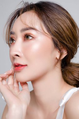 Güzel yüzlü ve mükemmel temiz tenli Asyalı bir kadın. Gri arka planda doğal makyajlı kadın modelin portresi. Kozmetik, vücut bakımı, estetik ameliyat, yüz bakımı, güzellik..