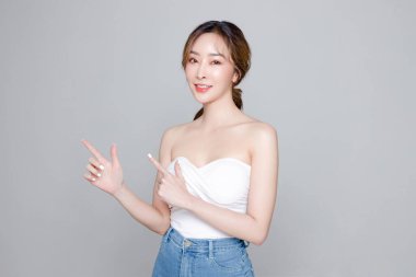 Güzel yüzlü ve mükemmel temiz tenli Asyalı bir kadın. Gri arka planda doğal makyajlı kadın modelin portresi. Kozmetik, vücut bakımı, estetik ameliyat, yüz bakımı, güzellik..