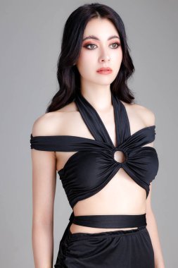 Kendine güvenen, zarif, modaya uygun, siyah seksi elbiseler giyen, beyaz arka planda mükemmel vücut pozu veren bir kadın. Kopyala, boşluk, Makyaj.