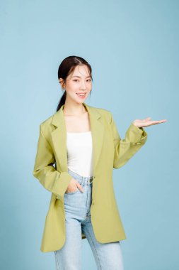 Mutlu gülümseyen, başarılı, 20 'li yaşlarda, sıradan, yeşil moda ceketli, pastel mavisi arka planda izole edilmiş bir fotokopi alanı olan iş kadını. Kadın girişimciler ya da ofis çalışanı konsepti.