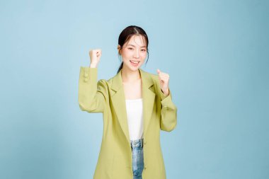 20 'li yaşlarda, sıradan moda ceketli genç ve başarılı bir çalışan kolları pastel mavisi arka planda izole bir şekilde birinci sınıf jest yapıyor. Kadın girişimciler, ofis çalışanı konsepti.