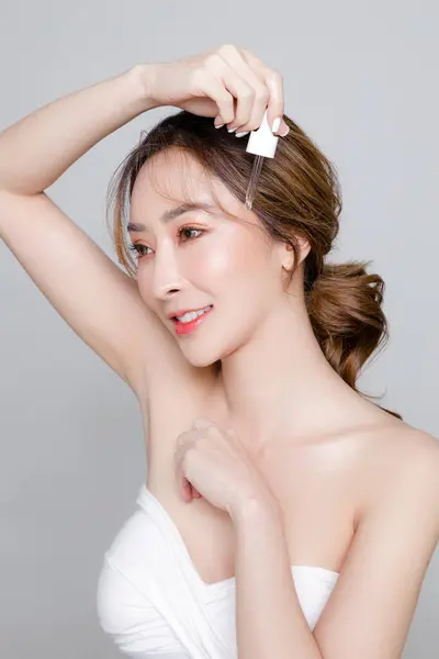 美しい顔と完璧なきれいな新鮮な肌を持つアジアの女性 女性モデルの肖像画は グレイの孤立した背景に彼女の顔に血清を適用します 化粧品 ボディケア プラスチック手術 — ストック写真