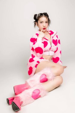 Uzun boylu, güzel, Asyalı bir kadın. Yüzü makyajlı ve beyaz arka planda izole bir şekilde oturan, kalp izi olan mükemmel ince vücutlu bir kadın. Valentine, aşkım, estetik ameliyat konsepti.
