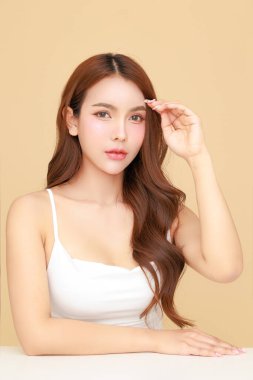 Güzel, genç Asyalı kadın model uzun saçlı, doğal makyajlı izole edilmiş bej arka planda temiz ciltli. Tatlı kız portresi, yüz bakımı, vücut bakımı, güzellik ve güzellik merkezi..