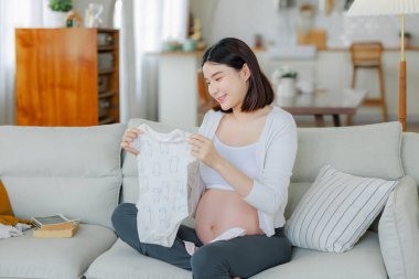 Genç Asyalı mutlu hamile kadın yatakta oturup rahatlıyor ve sırt ağrısına dokunuyor. Aile planı, hamilelik, annelik, insanlar ve beklenti konsepti