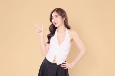 Güzel Asyalı, kıvırcık saçlı, uzun kıvırcık saçlı, Koreli makyajlı, parlak yüzlü, sağlıklı ciltli, gülümseyen, izole edilmiş bej arkaplandaki boşluğu gösteren bir gülümseme..