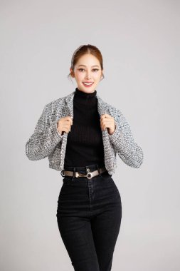 Asyalı zeki, mutlu girişimci iş kadınının portresi. Gri arka planda rahat bir takım elbiseyle gülümsüyor. KME kavramı.