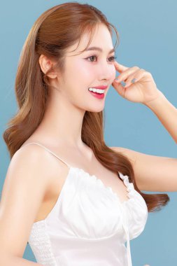 Pretty Asian beauty woman curly long hair with Korean makeup glowing face and healthy facial skin portrait smile on isolated blue background. clipart