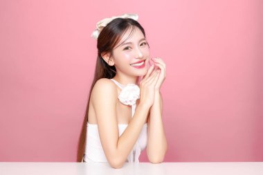 Güzel Asyalı kadın model uzun saç mükemmel temiz ten tebessümü izole pembe arka planda. Portre zarif bayan güzellik blogcusu stüdyoda makyaj sanatçısı. Cilt bakımı, estetik ameliyat, spa konsepti.