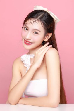 Güzel Asyalı kadın model uzun saç mükemmel temiz ten tebessümü izole pembe arka planda. Portre zarif bayan güzellik blogcusu stüdyoda makyaj sanatçısı. Cilt bakımı, estetik ameliyat, spa konsepti.
