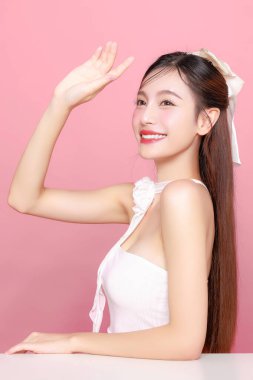 Güzel Asyalı kadın model uzun saç mükemmel temiz ten tebessümü izole pembe arka planda. Portre zarif bayan güzellik blogcusu stüdyoda makyaj sanatçısı. Cilt bakımı, estetik ameliyat, spa konsepti.