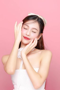 Güzel Asyalı kadın model uzun saç mükemmel temiz ten tebessümü izole pembe arka planda. Portre zarif bayan güzellik blogcusu stüdyoda makyaj sanatçısı. Cilt bakımı, estetik ameliyat, spa konsepti.