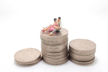 Küçük figürlü bir aşık sikkelerin üzerine oturur.