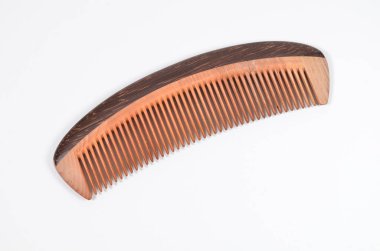 a closeup brown wooden comb on a white background