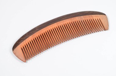 a closeup brown wooden comb on a white background