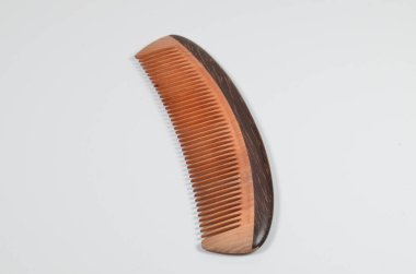 a closeup brown wooden comb on a white background