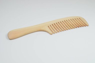 a closeup brown wooden comb on a white background