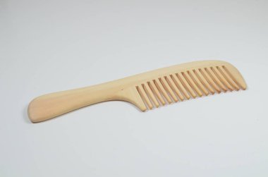 a closeup brown wooden comb on a white background