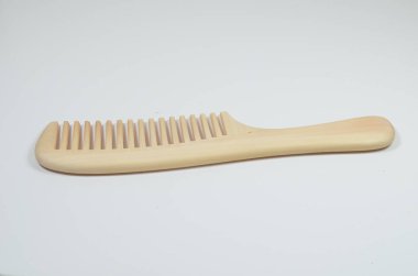 a closeup brown wooden comb on a white background