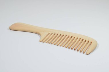 a closeup brown wooden comb on a white background