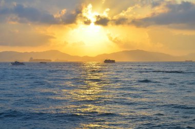 Güneş ışınları denizin üzerinde bulutların arasından fışkırıyor.