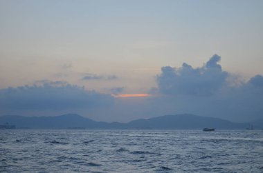 Güneş ışınları denizin üzerinde bulutların arasından fışkırıyor.