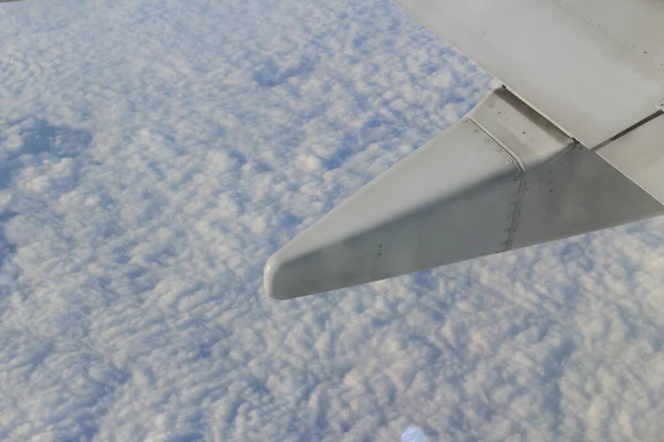 the Wing of the plane on sky background - plane wing with cloud patterns