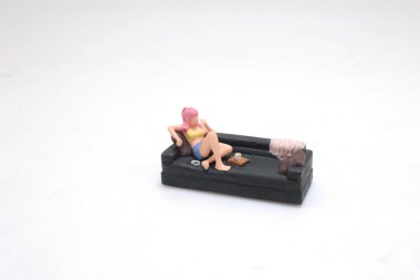 Bir kadın figürü kanepede oturuyor ve yukarı bakıyor.