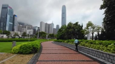 Tamar Park 'ta arka planda Hong Kong hükümet binaları olan bir sokakta yürüyen adam, 17 Mayıs 2023.